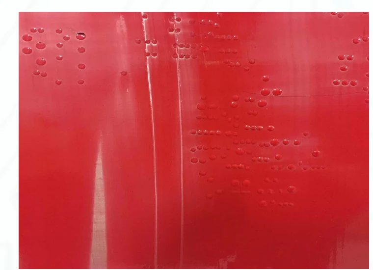 Copper stencil with red glue before cleaning